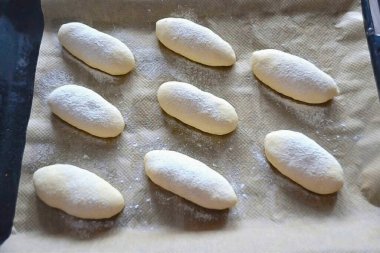 Çörekleri bir yemek tepsisine koyun, dikişler aşağı. Çörekleri süzgeçten un ile hafifçe toz al. 30 dakika boyunca kanıtla..