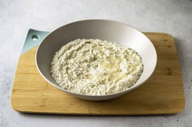 Büyük bir kasede unu sıcak su, tuz ve sebze yağıyla birleştir. Hamuru topa çevir..