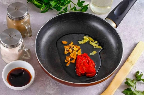 Pour vegetable oil into a frying pan, add tomato paste or ketchup, add garlic: dried or pressed fresh. Peel some of the ginger, cut into slices and place in butter.