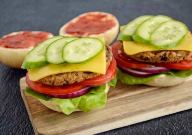 Vejetaryen peynirini tavada yumuşayana kadar erit, sonra pirzolaya geç. Sonra bir parça salatalık koy, üstüne ketçap koy ve ekmeğin diğer yarısıyla ört..