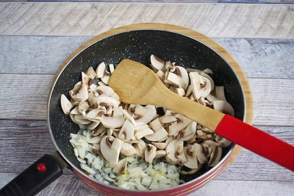 把橄榄油放在锅里加热 切碎洋葱 搅拌至透明 加入细切碎的蘑菇 煮至液体蒸发 — 图库照片