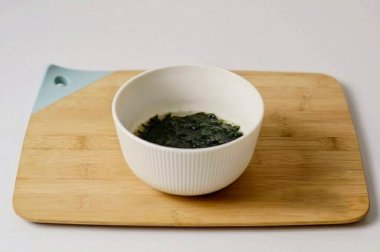 Wakame yosunlarının üzerine sıcak su dök, balık çeşnisini ekle, 5 dakikalığına ayrıl. Sonucu sıvıyı süzer..