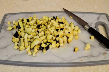 Patlıcanları kesme tahtasının üzerinde küp şeklinde kes..