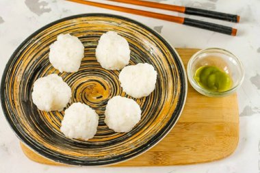 Ellerinizi suda ıslatırken biraz pirinç aşırın ve avuçlarınızda bir top oluşturun. Bu yüzden, birkaç tane daha boşalt..