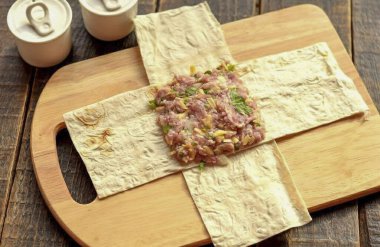 İnce bir yaprak pita ekmeğini 10 'a 25 cm boyutlarında eşit şeritlere ayır. Şeritleri birbiri ardına haç şeklinde katla. Tamam mı? Ortasına birkaç yemek kaşığı koy ve aşağı bastır..
