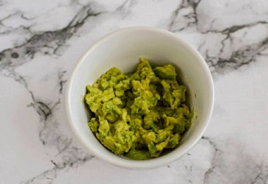 Avokadoyu soy, sonra da püre olana kadar çatalla ez. Tadına limon suyu, sarımsak, karabiber ve tuz ekle..