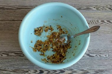 Geniş bir kase al. Soğanı rendele ve sarımsak doğrayıp rendele. Acı kırmızı biber, meyveli sandviç, kişniş, karabiber ekleyin. Karıştır.