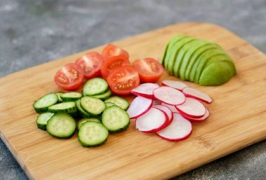 Turp ve salatalığı dilimlere ayır. Kirazlı domatesleri ikiye böl. Avokadoyu soy, yarısını enine kestir..