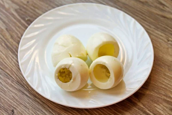 Boil the eggs after boiling for 12 minutes. Pour cold water over eggs, cool and peel. Cut off the bottom of the egg, on the wide side, and carefully remove the yolk without damaging the white.