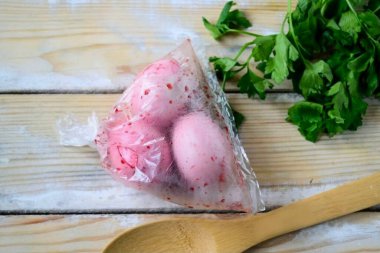 Çantaya yiyecek boyası dök ve biraz su ekle. Boya oldukça yoğunlaşmış olmalı. Yumurtaları bir çantaya koy ve bağla, yumurtaları salla kabukları boyamak için..