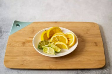 Kesme tahtasındaki kireç ve limonu dilimleyin..