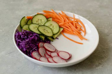 Salatalığı ve turpu dilimleyin, Kore rendesindeki havuçları rendeleyin, lahanayı ince ince doğra..