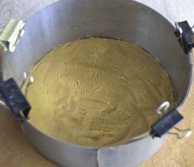 Küfü hazırlayın (23 cm çapında bir pasta halkam var). Yüzüğü kesme tahtası gibi sert bir yüzeye yerleştir, alt kısmı plastik ambalajla veya parşömeni dizerek sıkılaştır. Çevreye asetat bant yerleştirilebilir. Kırıntıları üstüne koy.