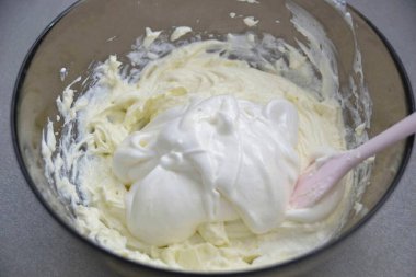 Krem peynirine çırpılmış protein ekle, silikon spatulayla yavaşça karıştır..