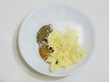 Sarımsağı soy, rendeleyin. Tuz ve baharatlı bir kaseye ekle. Eşit karışana kadar karıştır.