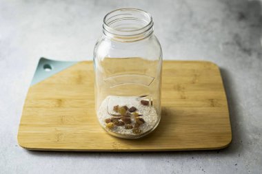 Temiz, sterilize edilmiş kavanoza kuru üzüm, sitrik asit, maya ve şeker ekle..