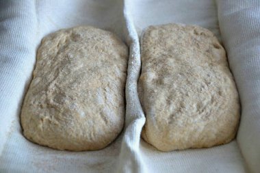 Bir peçeteye bol miktarda un serpin, ciabatta kurusıkı koyun, kenarlara küçük havlularla destek olun, kurusıkı havlular arasında katlayın. Hamur yarım saat dinlensin..