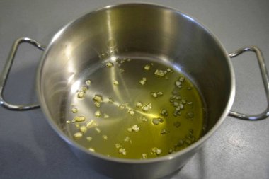 Kalın duvarlı tencere ya da tencereye zeytinyağı dök, ince doğranmış sarımsak ve hafif kızarmış et ekle..