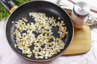 Soğanları soy ve suda durula, küçük küplere böl ve sebze yağını kızartma tavasında 2-3 dakika boyunca geç, ta ki altın kahverengiye kadar..