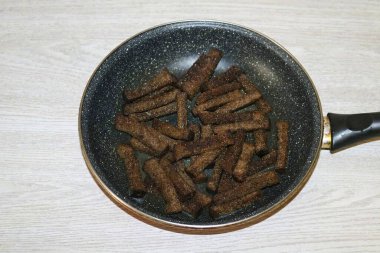 Orta sıcaklıkta kızarana kadar her taraftaki kızarmış ekmekleri kızart. Gerektiğinde yağ ekle.