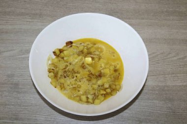 Patateslerin yağını boşalt, yağlanmış yumurtalara kızarmış patates ve soğan ekle. İyi karıştır, hafif tuz.