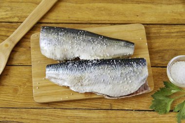 Erimiş taze ringa balığını karın tarafından kes ve iç organlarını çıkar. Kafasını, kuyruğunu kes, yüzgeçlerini kes ve akan suyun altında durula. Kaba tuzu ayırmadan tuz, ellerinle iyice ovala..