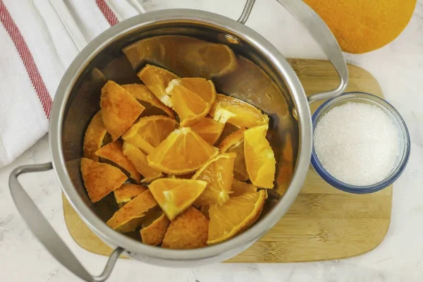 沸騰した水で柑橘類を拡大し オレンジからゼストを除去する それは苦いことができます 他のレシピでそれを使用してください 果物を四分の一に切り 存在する場合は種子を取り除きます スライスにカットし 鍋に配置 — ストック写真