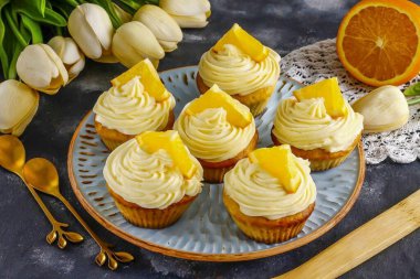 Kekleri istediğiniz şekilde şekillendirme kremiyle süsleyin. Kalan portakalların yarısını dilimleyin ve onlara servis ederken de garnitür olarak dilimleyin.