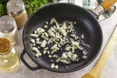 Soğan ve sarımsak soy, suda durula. Soğan ve sarımsak parçalarının yarısını küp küp küp doğra ve tavaya dök. Bitkisel yağ dök ve 2-3 dakika kadar kızart. Orta sıcaklıkta altın kahverengiye kadar..