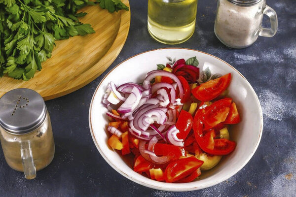 Разрежьте половину красного лука пополам кольца и добавьте в миску вместе с промытыми и нарезанными помидорами черри.