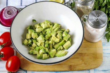 Avokadoyu ikiye böl ve kabuğunu ve kemiğini çıkar. Hamuru küp küp doğra ve derin bir kaba boşalt..