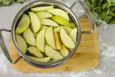 Sıcak su dök ve tencereyi ocağın üzerine koy. İçindekileri kaynat, sonra ısıyı azaltıp 15-20 dakika kadar kompostu kaynatın. Dilimler yumuşak olana kadar..