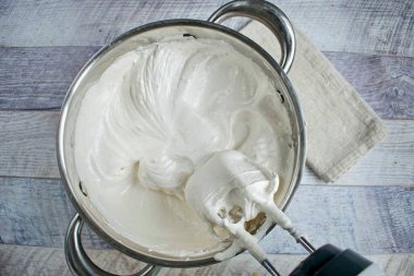 Kütleyi büyük bir konteynere aktarın (en az 3 litre hacim). Karışımı yüksek hızda yenmeye başla ve sıcak şurubu ince bir dereye dök. 5-7 dakika çırp.