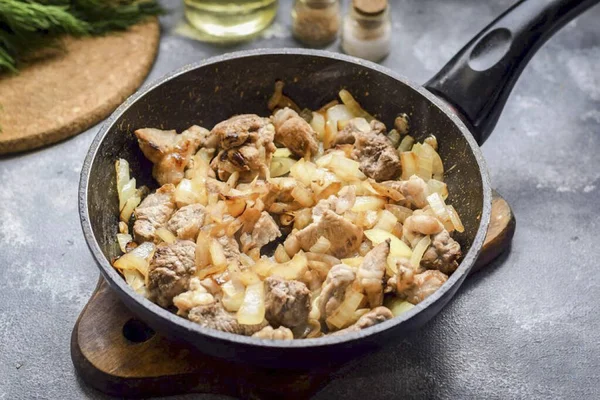 Preheat a frying pan, brush with oil, add meat and onions. Fry until golden brown, stirring for 3-4 minutes.