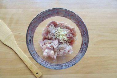 Tavuk fileto ve kalçaları kaseye koyun. Doğranmış sarımsak ekle.