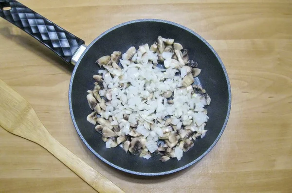 キノコと鍋にみじん切り玉ねぎを追加します — ストック写真