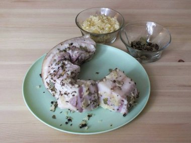 Domuz yağını salamuradan çıkar. Kağıt havluyla kurut. Birkaç yerde dikey kesikler açın. Sarımsak ve baharatlarla bol bol yay..