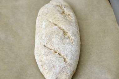 Bir saat sonra, iş parçasını bir yemek tepsisine aktarın, keskin bir bıçakla kesim yapın. İlk 10 dakikayı maksimum sıcaklıkta pişirin, sonra sıcaklığı 180-200 dereceye düşürün, aşırı ısıyı serbest bırakın ve 50 dakika daha pişirin..