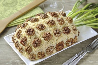 Kalan peyniri iyice rendele ve salatanın her tarafına serp. Salatayı ceviz yarısıyla süslemek ve tabana ananas yapraklarını taklit ederek yeşillik koymak kaldı. Afiyet olsun.!