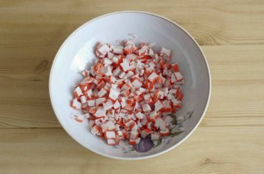 Yengeç çubuklarını orta küp şeklinde kes (dekorasyon için bir çubuk ayır). Salata kasesine transfer et..