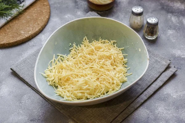 把硬奶酪放在细碎的磨盘上 然后把奶酪刨花放到一个深碗里 — 图库照片