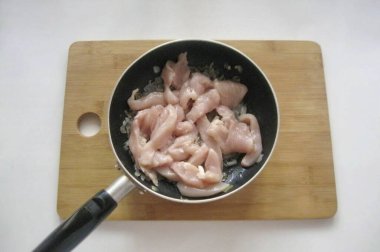 Tavuk filetosunu yıka ve küçük parçalara böl. Tavaya soğan ekle..