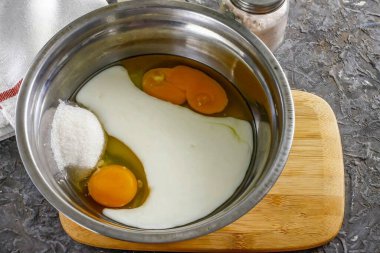 Tavuk yumurtalarını derin bir konteynere koy, yağ içerikli kefir dök, tuz ve şeker ekle. Suyu dökün ve her şeyi 1-2 dakika çırpın..