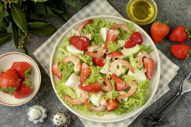 Alışılmadık, ama çok lezzetli karides ve çilekli salata hazır. Yemek pişirdikten hemen sonra servis et. Hafif, düşük kalorili ve çok lezzetli bir salata arkadaşlarla buluşmaya hazırlanabilir. Bir bardak soğuk şampanya harika bir ilave olur.