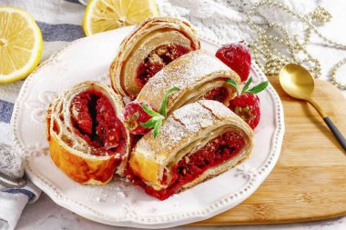 Gently dust strudel with powdered sugar, cut into pieces and place on a plate. Serve with a scoop of ice cream, berries, and a hot drink. clipart