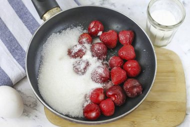 Peel the strawberries from the tails, put in a frying pan or cauldron, add granulated sugar. Protomit the berries with sugar for about 3-5 minutes. clipart