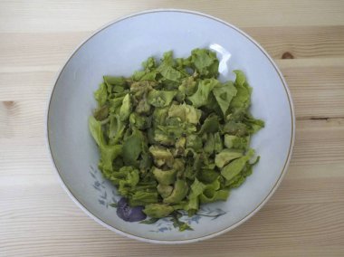 Derin bir salata kasesinde, marulu (ellerinizle parçalara ayırın) ve rastgele doğranmış avokadoyu.