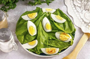 Haşlanmış tavuk yumurtası soy, suda durula ve çeyreklikleri kes. Ispanağın üstüne koy. Haşlanmış bıldırcın yumurtalarını ikiye bölerek kullanabilirsin..