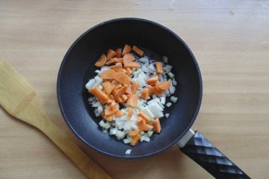 Havuç ve soğanları doğra, ama çok kaba olmasın ve tavaya veya güvece koy. Soğanlar şeffaf olana kadar sebze yağı dök ve kızart..