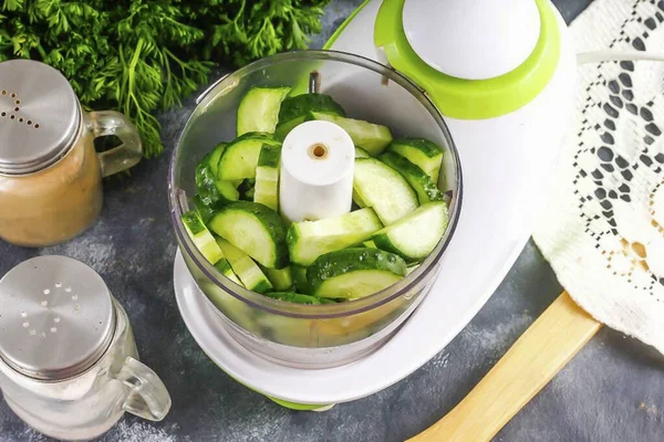 Rinse the cucumbers in water, rinsing off the dust and thorns, cut the tails from the vegetables. Cut them into small slices and pour into the chopper bowl.
